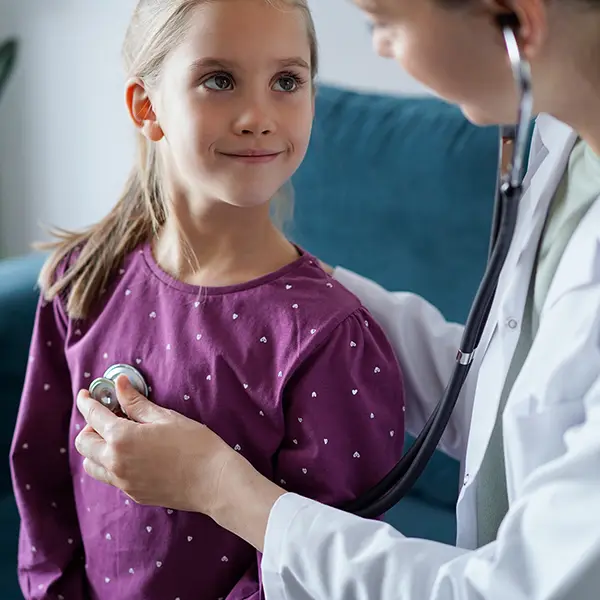 Young girl in magenta shirt having her heartbeat monitored by a female physician.